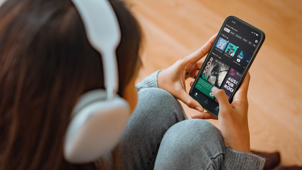 Woman wearing headphones looking at a phone.